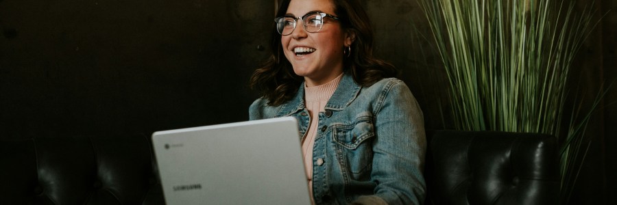 A person laughing while holding a laptop