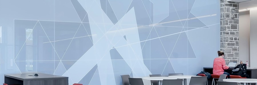 A person in an office-like space sitting way over to one side by themself in an otherwise empty room