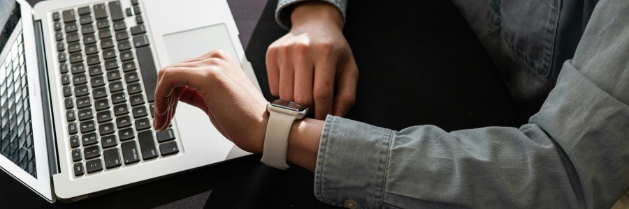 A laptop and a person looking at their watch