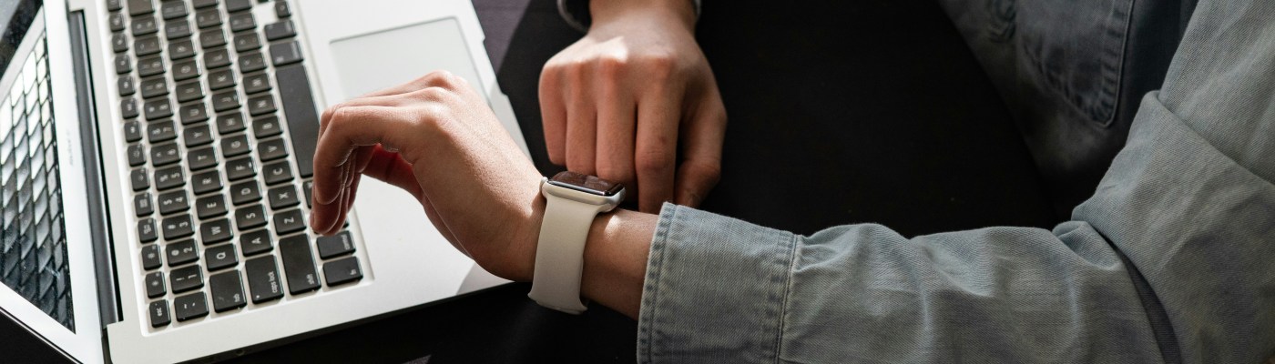 A laptop and a person looking at their watch